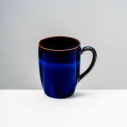 Dunkelblaue, glänzende Keramik-Kaffeetasse mit Henkel vor hellem Hintergrund, frontal aus leicht erhöhter Perspektive aufgenommen