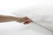Nahaufnahme eines weißen Tempur Schlafkissens 80 x 40 cm mit einer Hand, die den Reißverschluss öffnet.