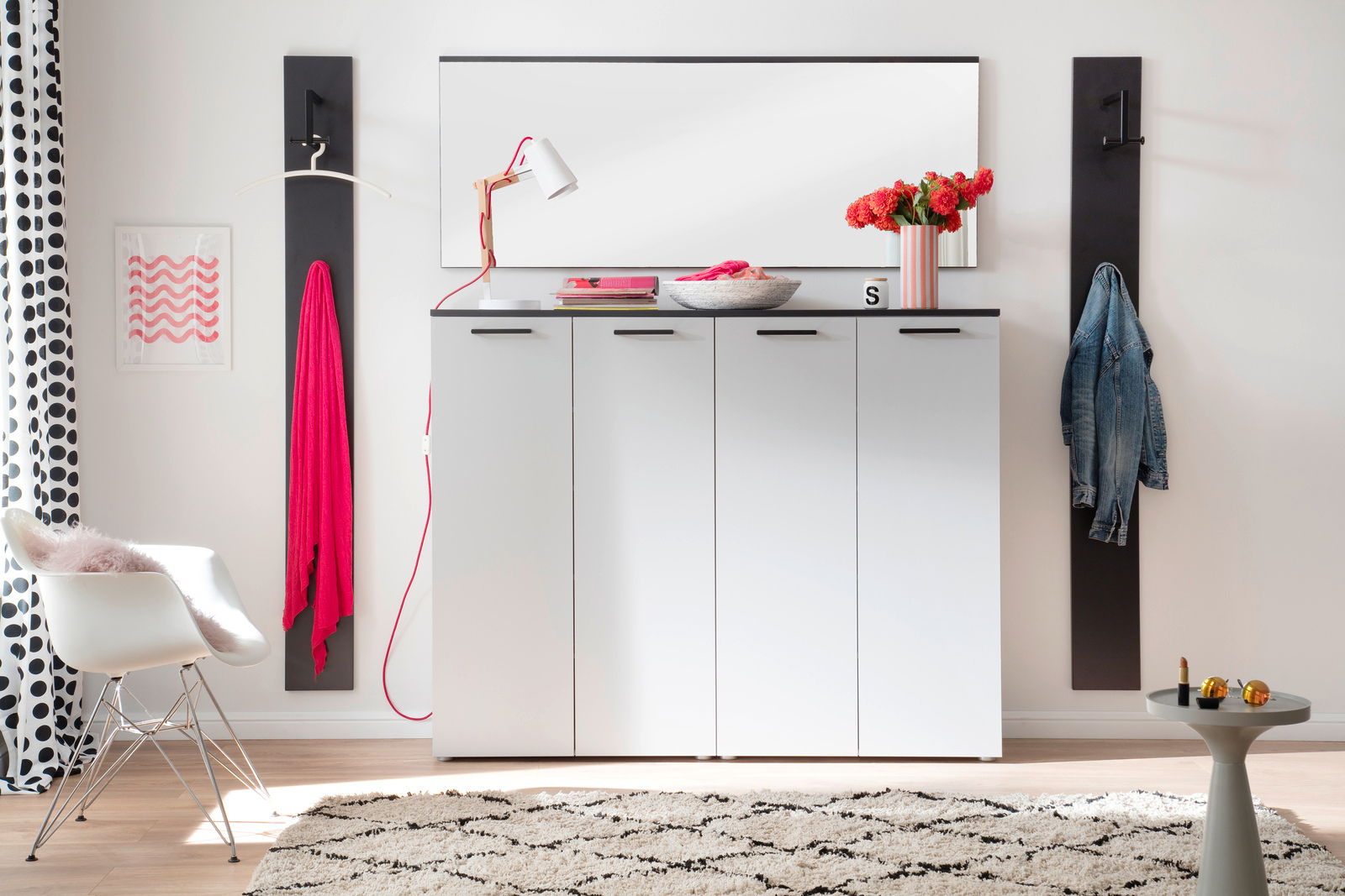 Moderano Spiegel ALMADA Moderner Flur mit weißem Schrank, darüber ein rechteckiger Spiegel, seitlich Garderobenhaken mit Kleidung, aus der Frontalperspektive.