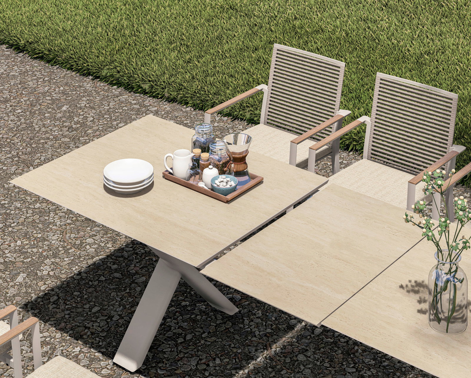 Garten Ausziehtisch aus hellem Holz mit modernen Stühlen, von oben fotografiert, auf einer Terrasse mit grüner Wiese im Hintergrund.