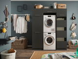 Moderner Waschraum mit einem schwarzen Hochschrank, der eine Waschmaschine und einen Trockner enthält. Perspektive von vorne.