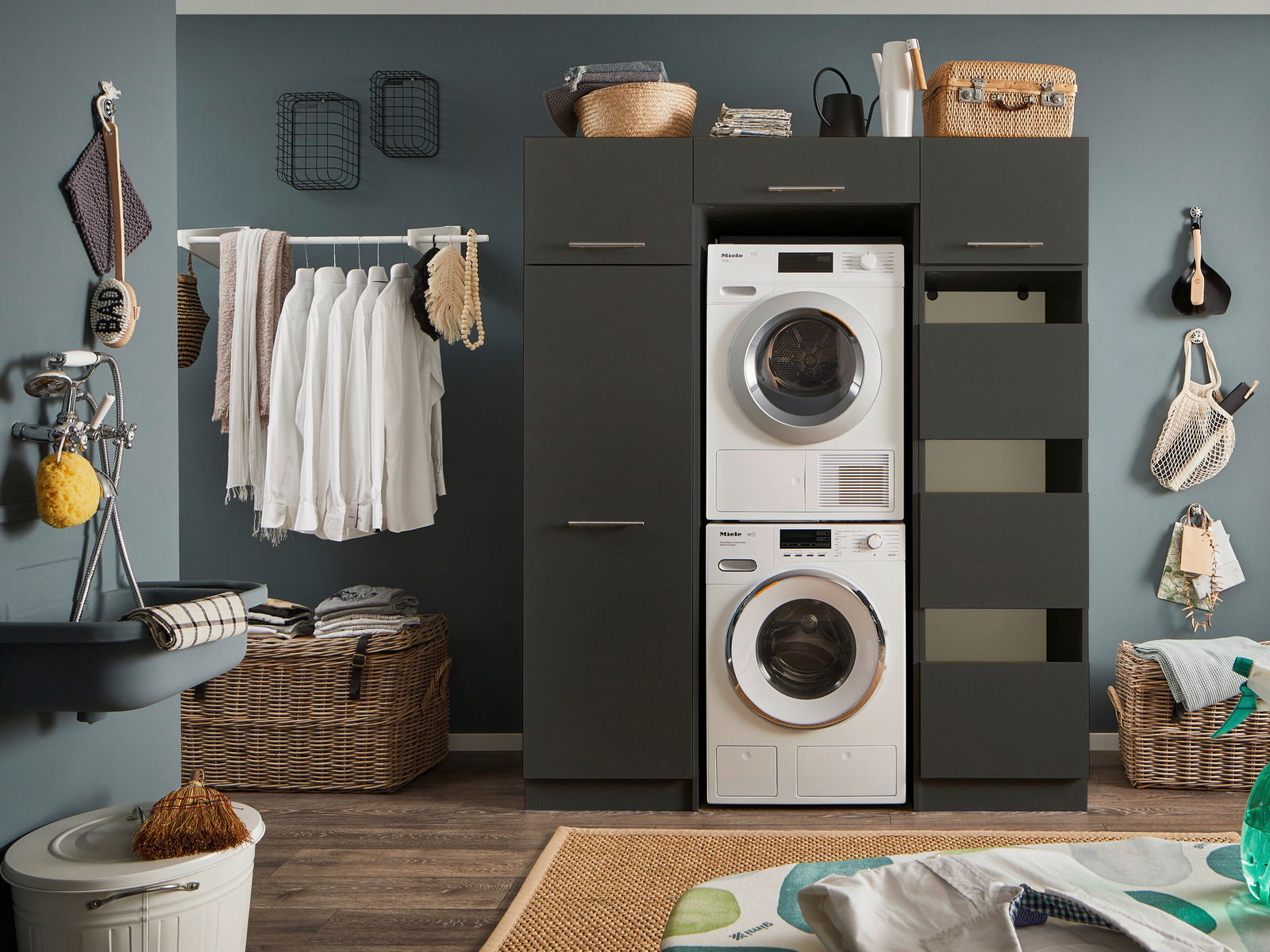 Moderner Waschraum mit einem schwarzen Hochschrank, der eine Waschmaschine und einen Trockner enthält. Perspektive von vorne.