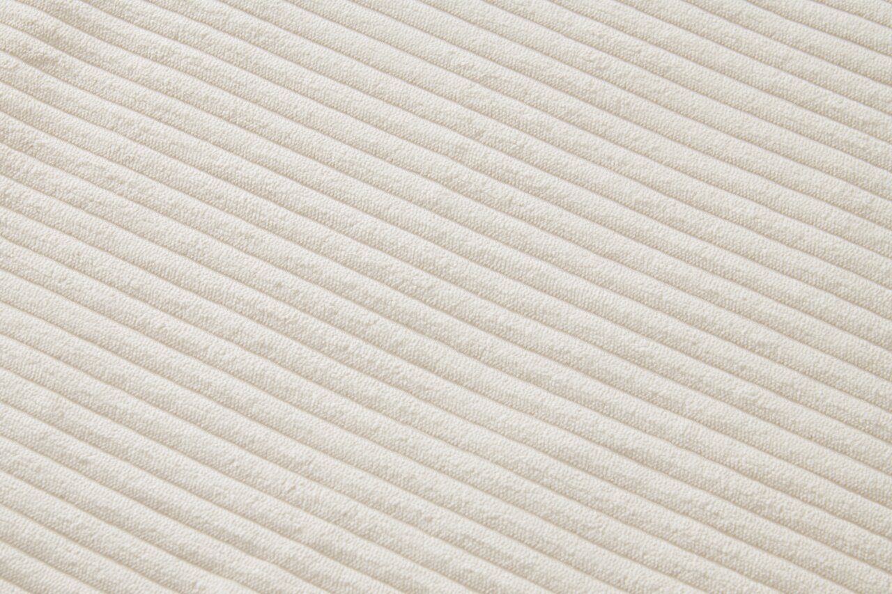 XORA Armlehnstuhl JESSY Nahaufnahme eines cremefarbenen, gerippten Stoffes in diagonaler Perspektive.