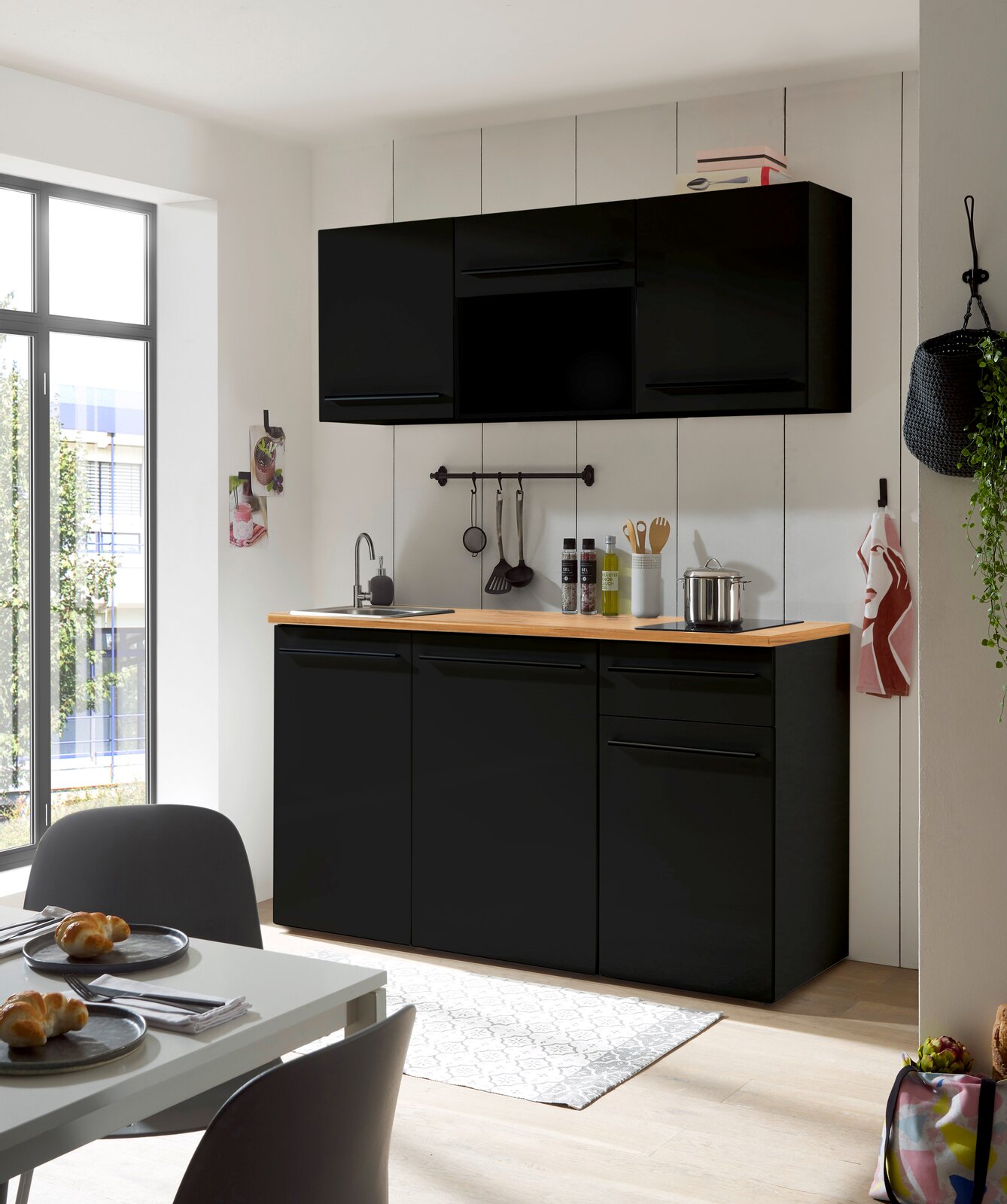 Yourkitchen Single-Küche 160 ohne E-Geräte JAZZ Moderne Single-Küche in schwarzem Design mit Holzarbeitsplatte, fotografiert aus einer leicht seitlichen Perspektive.