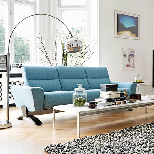 Modernes Wohnzimmer mit blauem Sofa, Couchtisch mit Büchern und Kunst an den Wänden.