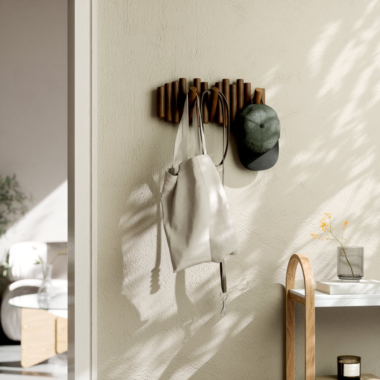 Wandgarderobe aus Holz mit mehreren Haken, an der eine Tasche und eine Mütze hängen, seitliche Perspektive.