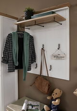 Garderobenpaneel mit Haken und Ablage, frontal fotografiert. Dekoriert mit Jacke, Schal, Tasche und Willkommensschild.