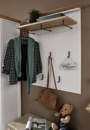 Garderobenpaneel mit Haken und Ablage, frontal fotografiert. Dekoriert mit Jacke, Schal, Tasche und Willkommensschild.