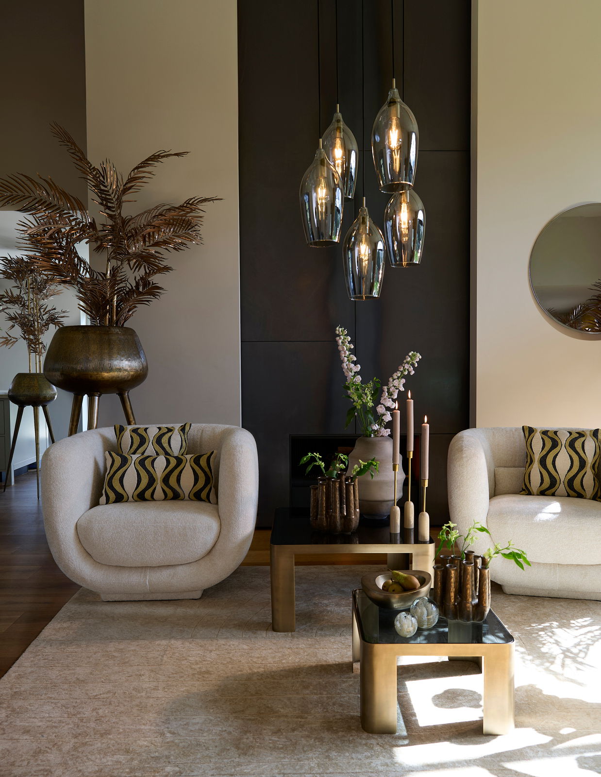 Moderne Hängeleuchte mit fünf Glühbirnen in eleganten, rauchgrauen Glasfassungen, hängend in einem stilvoll eingerichteten Wohnzimmer. Perspektive von vorne.