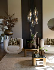 Moderne Hängeleuchte mit fünf Glühbirnen in eleganten, rauchgrauen Glasfassungen, hängend in einem stilvoll eingerichteten Wohnzimmer. Perspektive von vorne.