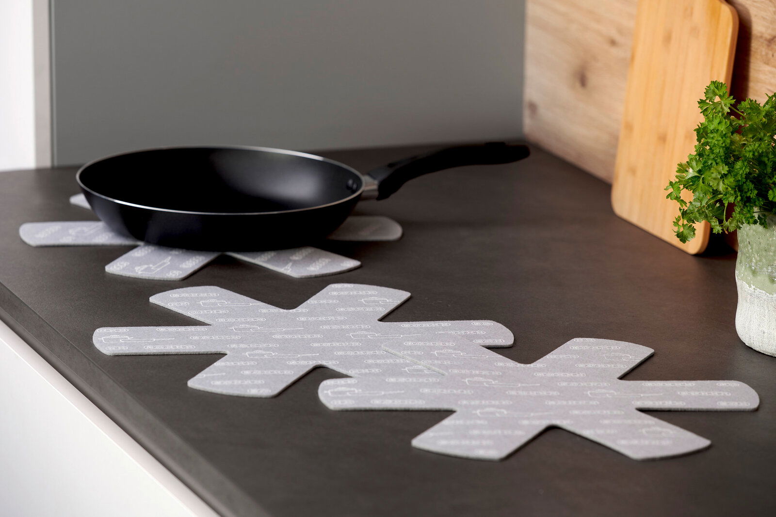 BOXXX Pfannenschutz 3tlg. Pfannenschutz in Sternform auf einer Küchenarbeitsplatte, mit einer Pfanne darauf platziert, seitliche Perspektive.