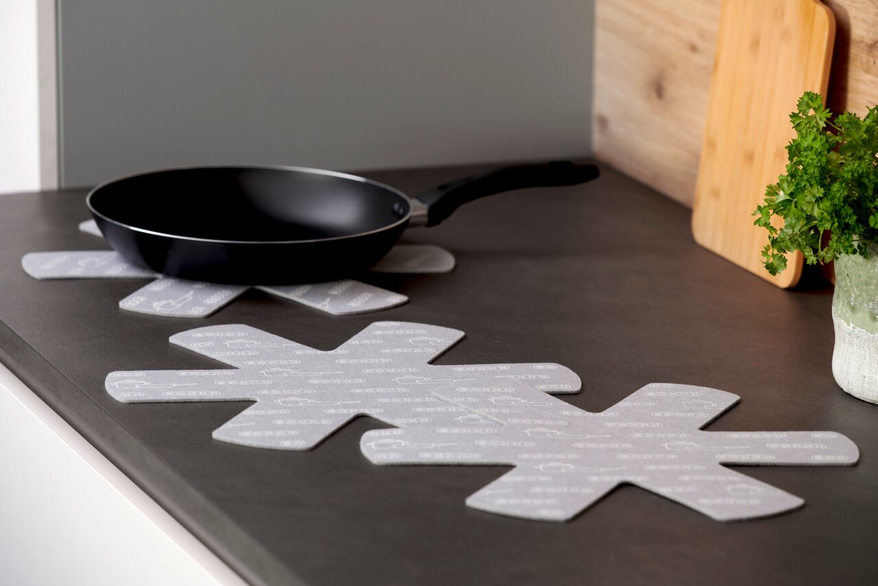 BOXXX Pfannenschutz 3tlg. Pfannenschutz in Sternform auf einer Küchenarbeitsplatte, mit einer Pfanne darauf platziert, seitliche Perspektive.