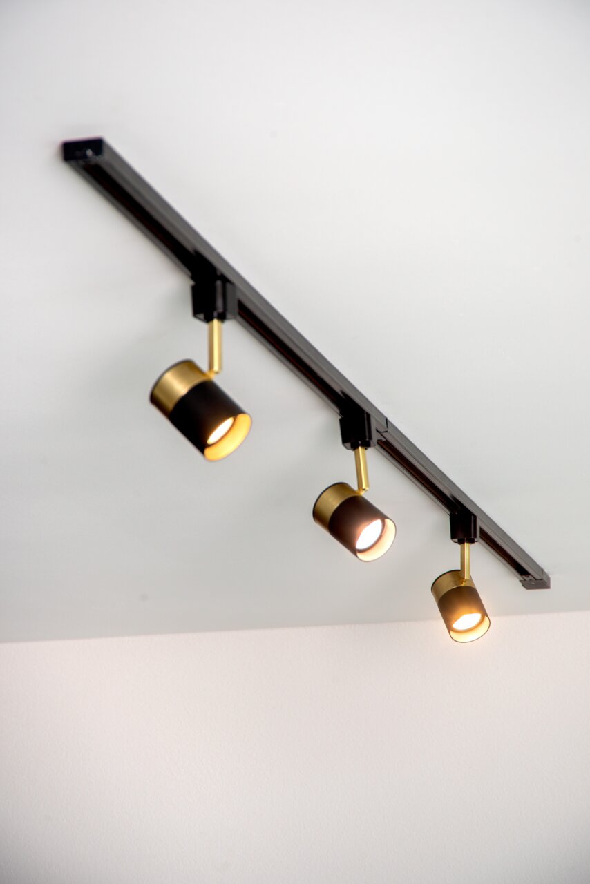 Dreifacher schwarzer Strahler FLORIS an einer Decke montiert, mit goldenen Akzenten, aus seitlicher Perspektive fotografiert.