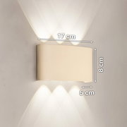 Weiße, moderne LED-Wandleuchte mit Up-&-Down-Lichtkegeln an grauer Wand, Maße 17 cm breit, 8 cm hoch, 5 cm tief, Frontansicht.