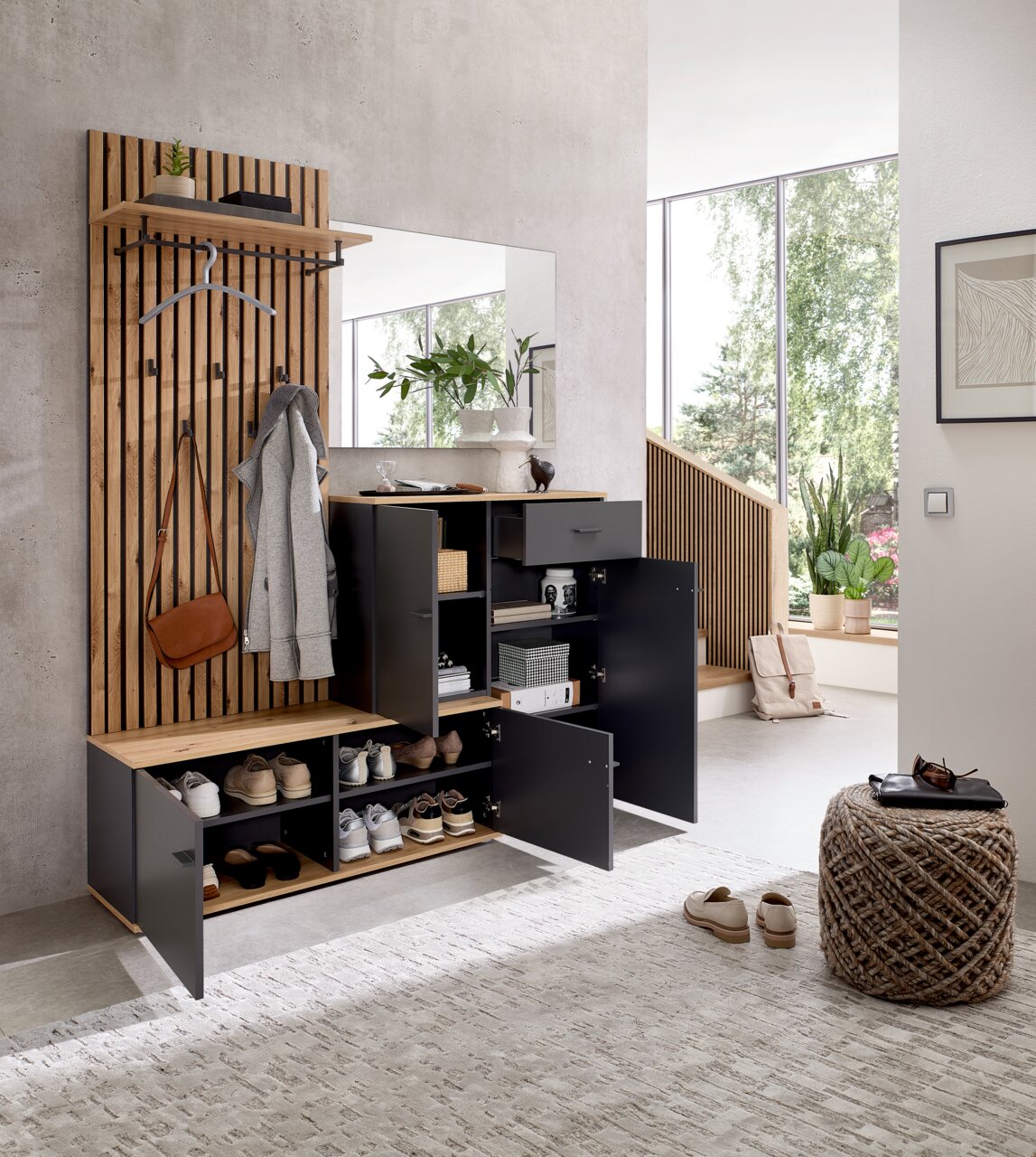 Moderne compacte kapstok met houten en metalen elementen, inclusief spiegel, kapstokhaken en opbergruimte, gefotografeerd vanuit een lichte hal.