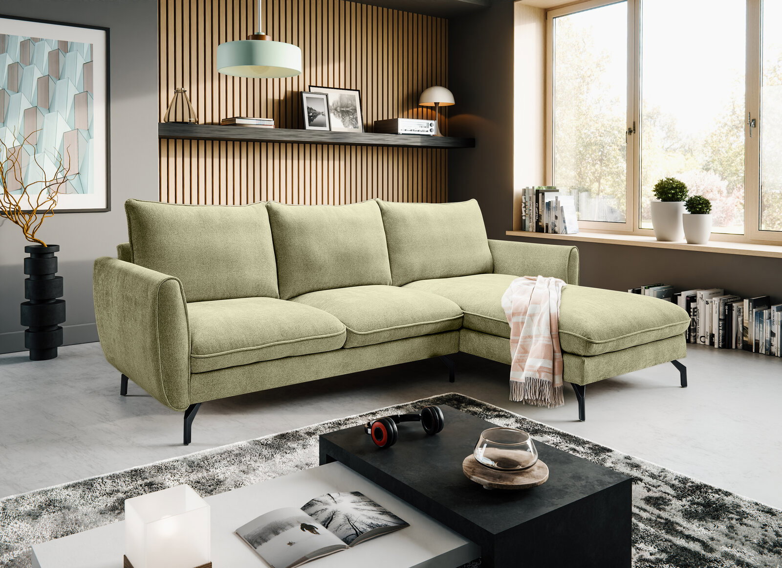 Hellgrünes L-förmiges Ecksofa mit Recamiere rechts und schwarzen Metallfüßen im modernen Wohnzimmer, fotografiert in frontaler leicht schräger Perspektive von links.