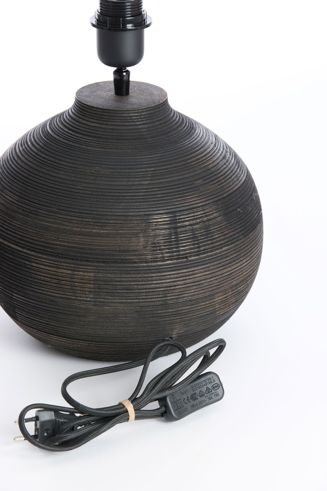 Nahaufnahme eines runden, gerillten Lampenfußes aus dunklem Holz mit schwarzem Kabel, seitliche Perspektive