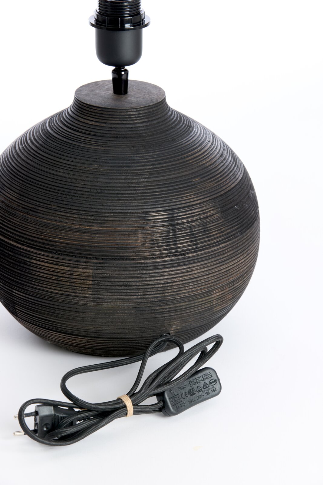 Close-up van een ronde, geribbelde lampvoet van donker hout met een zwarte kabel, gezien vanaf de zijkant