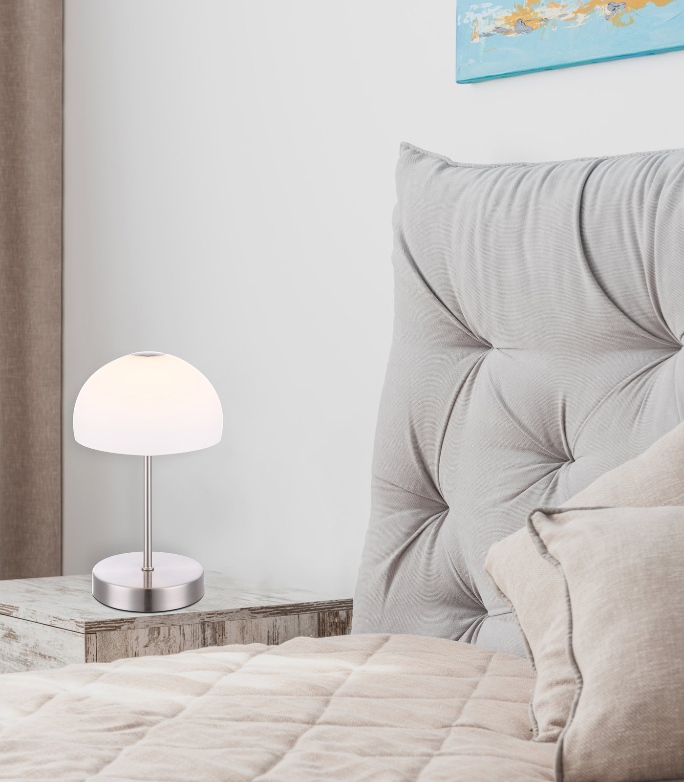 Moderne Tischleuchte SNOWFLAKE auf einem Nachttisch neben einem gepolsterten Kopfteil, seitliche Perspektive.