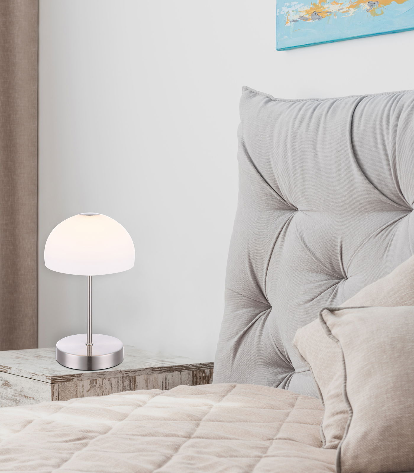 Moderne Tischleuchte SNOWFLAKE auf einem Nachttisch neben einem gepolsterten Kopfteil, seitliche Perspektive.