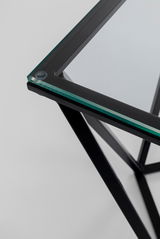 Nahaufnahme eines modernen Beistelltisches mit Glasplatte und schwarzem Metallrahmen, von oben betrachtet.