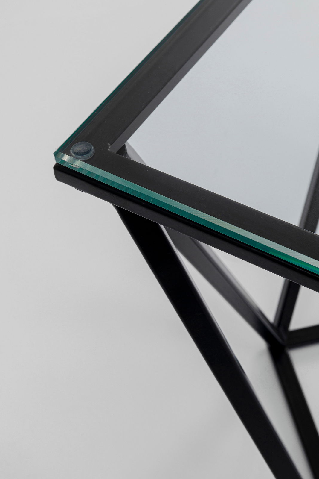 Nahaufnahme eines modernen Beistelltisches mit Glasplatte und schwarzem Metallrahmen, von oben betrachtet.