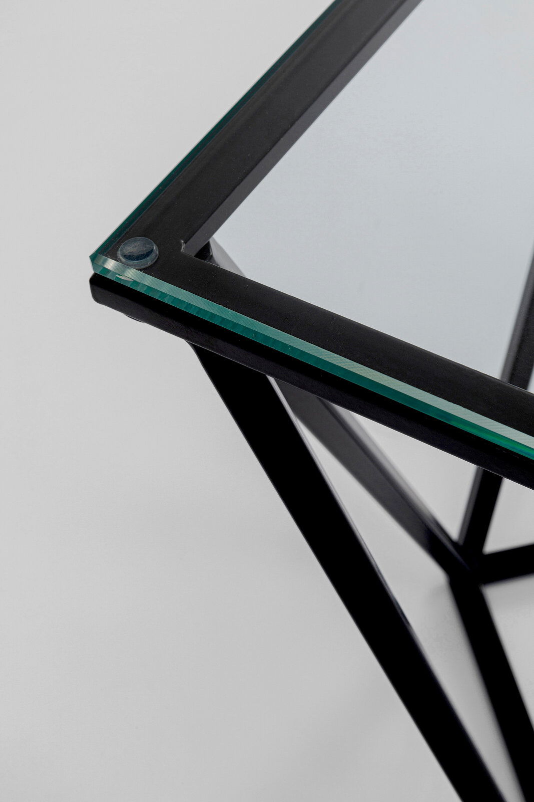 Nahaufnahme eines modernen Beistelltisches mit Glasplatte und schwarzem Metallrahmen, von oben betrachtet.