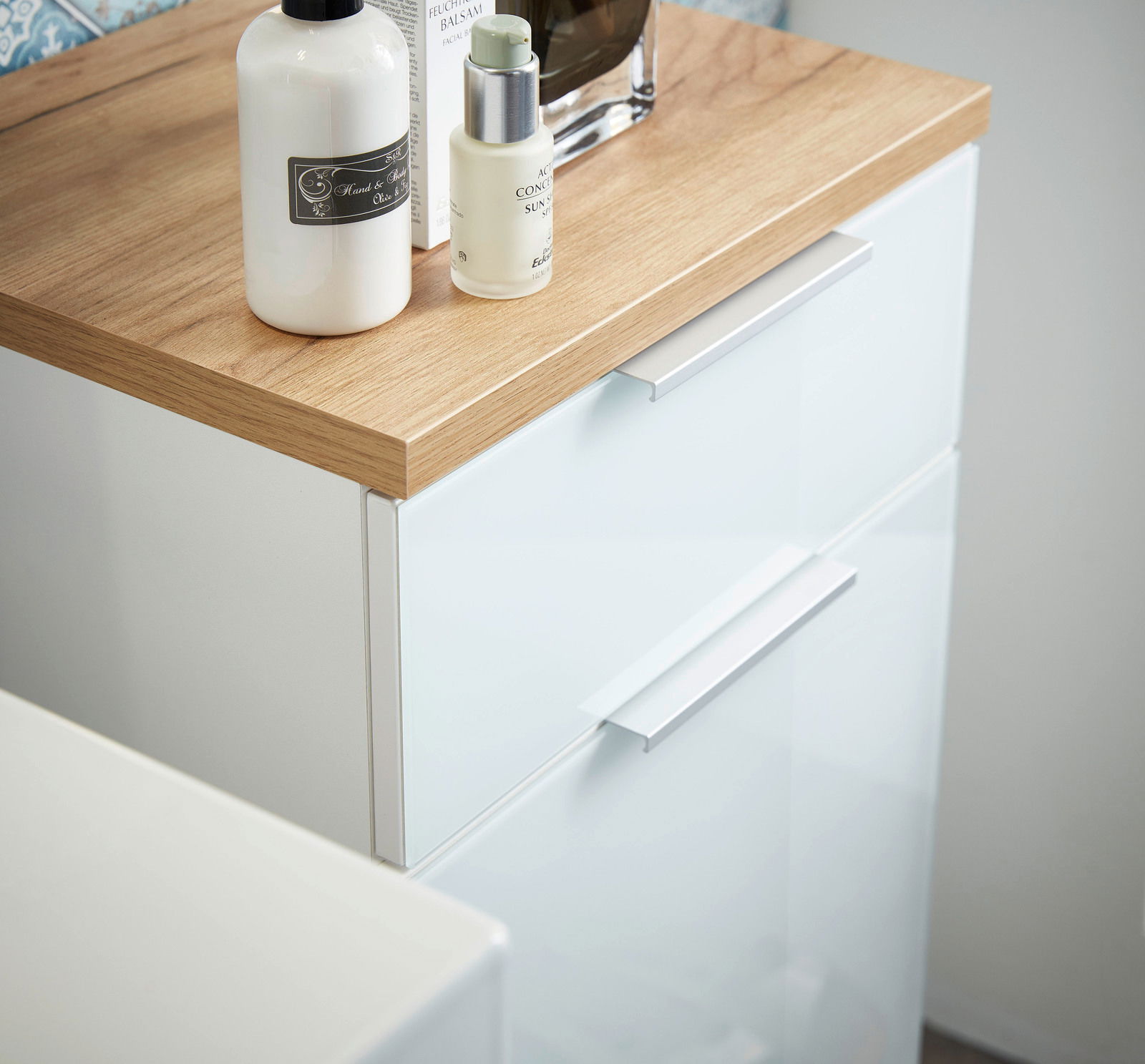 Nahaufnahme eines modernen Unterschranks mit weißer Front und Holzoberfläche, von oben fotografiert.