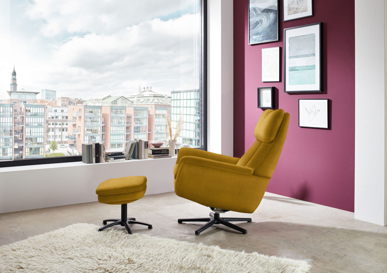 Gelber Sessel mit Hocker in modernem Wohnzimmer, seitliche Perspektive, mit Blick auf große Fenster und Stadtansicht.