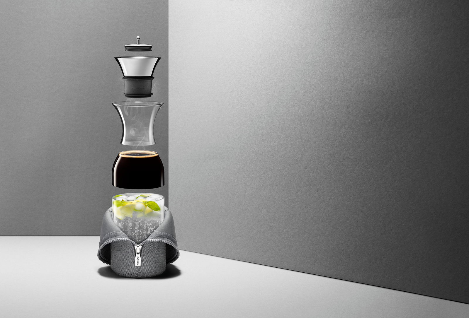 Eva Solo Kühlschrankkaraffe MASTER Explodierte Ansicht einer Kühlschrankkaraffe mit grauem Reißverschlussmantel, gefüllt mit Eis und Minze, Kaffee und Dampf, vor grauem Hintergrund.