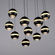 Verschillende moderne, bolvormige zwarte hanglampen met een rondomlopende warmwitte lichtband en een glazen lens hangen aan kabels tegen een grijze achtergrond, gezien vanuit een lichte onderhoek (onderzicht).