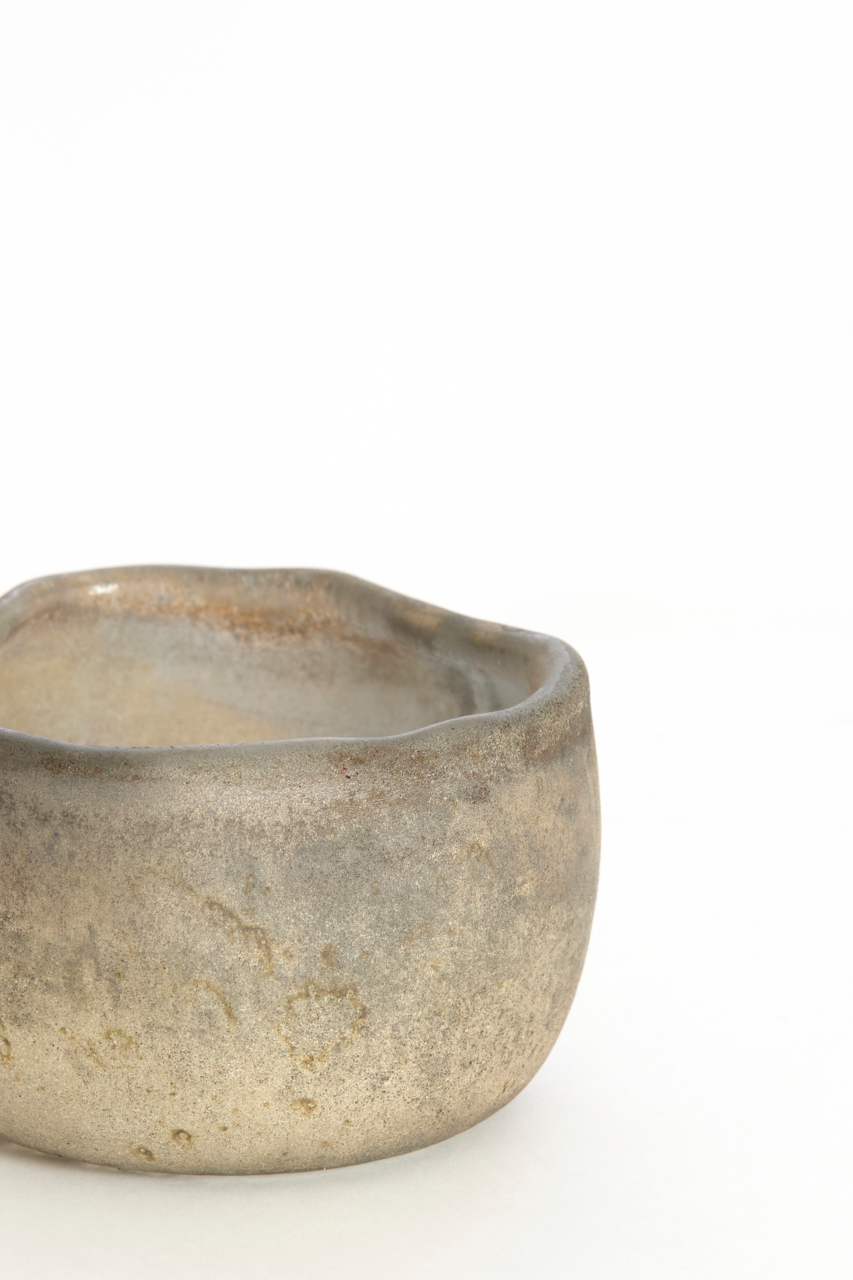 Nahaufnahme eines rustikalen, handgefertigten Teelichthalters aus Keramik mit unregelmäßiger Form und natürlicher Farbgebung.