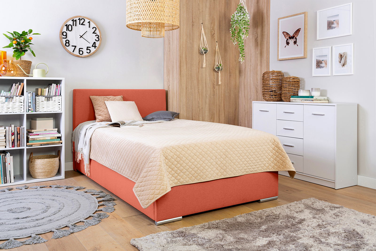 Gemütliches Schlafzimmer mit einem Boxbett in Korallenfarbe, umgeben von modernen Möbeln und Dekorationen, aus einer seitlichen Perspektive fotografiert.
