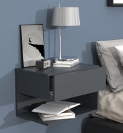 Modernes schwebendes Nachttisch-Wandregal in Dunkelgrau mit Schublade und offenem Fach neben dem Bett, dekoriert mit Tischlampe, gerahmtem Poster, Uhr und Büchern, frontale leicht seitliche Perspektive.