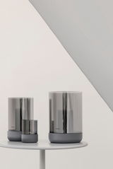 Drei Windlichter in verschiedenen Größen in Steel Gray auf einem weißen Tisch, seitliche Perspektive.