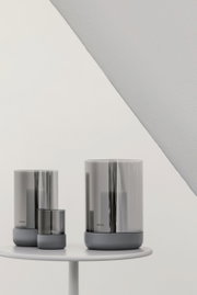 Drei Windlichter in verschiedenen Größen in Steel Gray auf einem weißen Tisch, seitliche Perspektive.