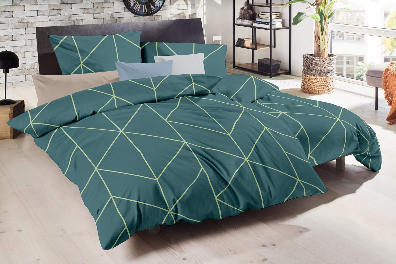 Petrolfarbene Bettwäsche mit geometrischem Linienmuster in Hellgrün auf einem Doppelbett, schräg von vorne in einem hellen Schlafzimmer fotografiert