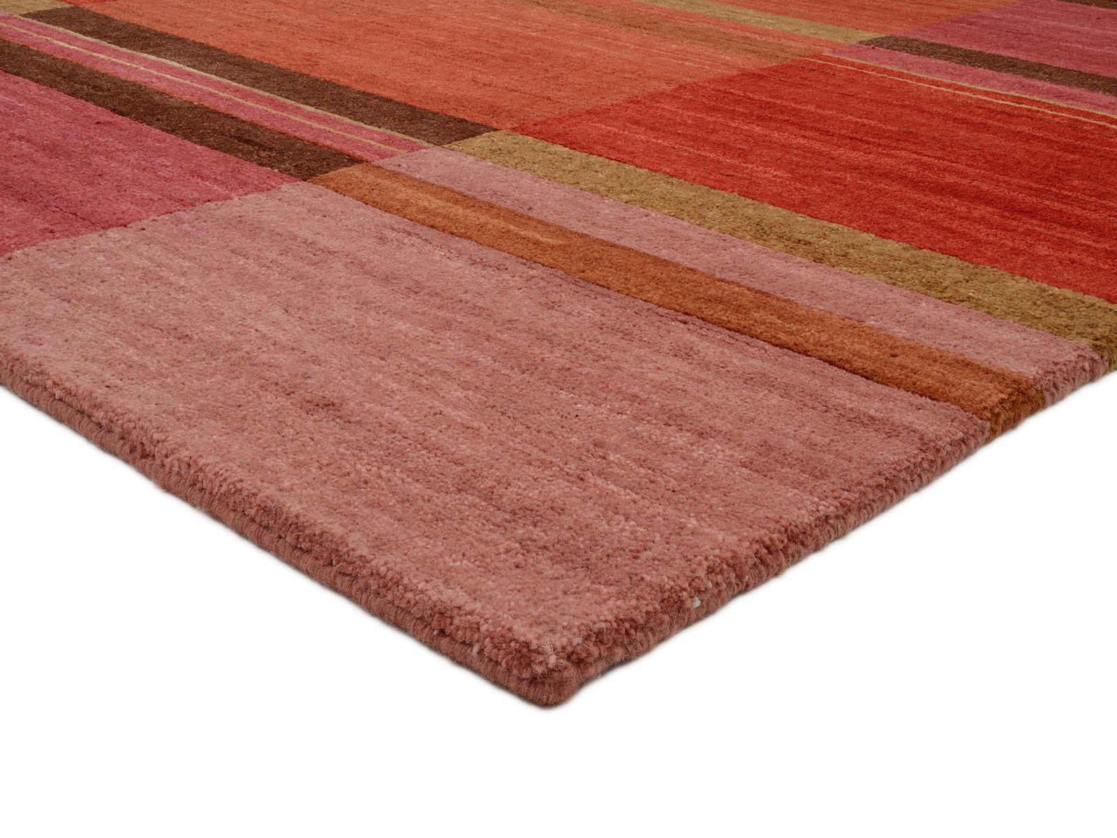 Nahaufnahme eines Wollteppichs mit bunten Streifen in Rot-, Rosa- und Brauntönen, perspektivisch von der Ecke aus gesehen.