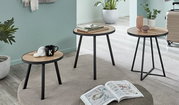 Drei runde Beistelltische mit Holzoptik-Tischplatten und schwarzen Metallbeinen im modernen Wohnraum, fotografiert aus leicht erhöhter schräger Perspektive.