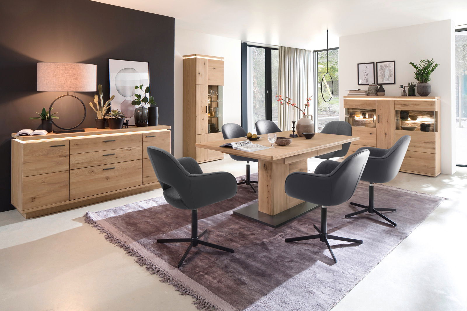 Moderne Esszimmer-Einrichtung mit Holztisch, grauen Stühlen und Sideboards in einem hellen Raum, seitliche Perspektive.