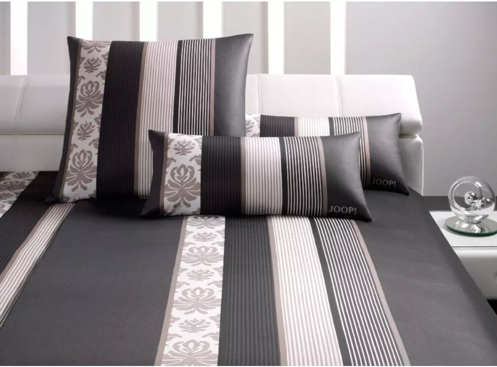Bettwäsche-Set mit modernem Streifen- und Blumenmuster in Schwarz, Weiß und Grau, auf einem weißen Sofa präsentiert.