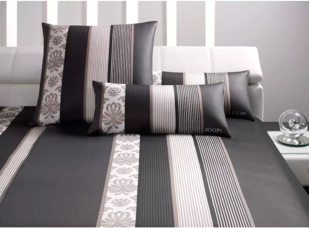 Bettwäsche-Set mit modernem Streifen- und Blumenmuster in Schwarz, Weiß und Grau, auf einem weißen Sofa präsentiert.