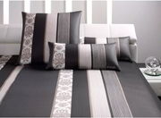 Bettwäsche-Set mit modernem Streifen- und Blumenmuster in Schwarz, Weiß und Grau, auf einem weißen Sofa präsentiert.