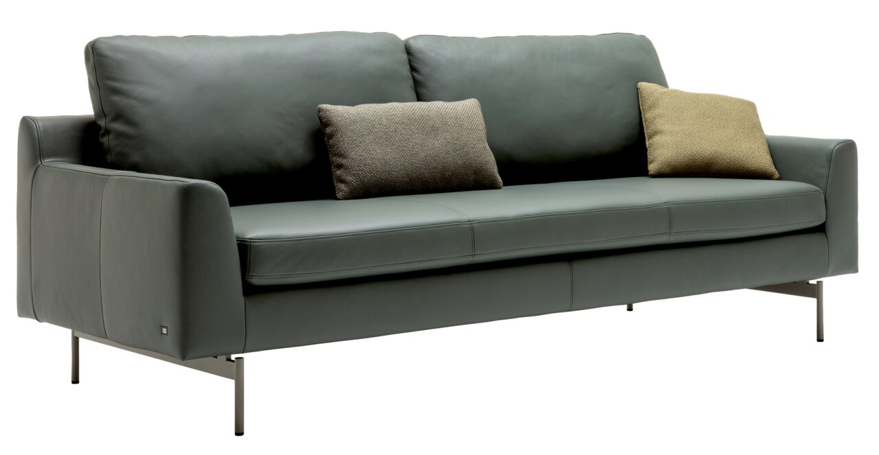 Modernes dreisitziges Sofa in grauem Leder mit zwei dekorativen Kissen, seitliche Perspektive