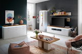 Modernes Wohnzimmer mit Sideboard, Vitrine, TV-Element und Couchtisch in heller, stilvoller Einrichtung. Perspektive von vorne.