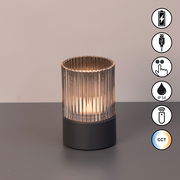 Akku-Windlicht mit geriffeltem Glaszylinder und dunklem Sockel, frontal betrachtet, mit Symbolen für USB-Ladung, Touch-Bedienung, IP54-Schutz, Fernbedienung und CCT-Farbtemperatur.