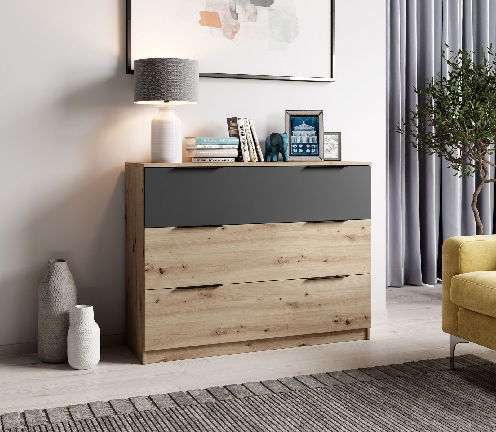 Moderne Kommode aus Holz mit drei Schubladen, obere Schublade in dunklem Grau, dekoriert mit Lampe, Büchern und Bildern, seitliche Perspektive