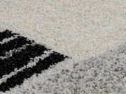 Nahaufnahme eines Teppichs mit geometrischem Muster in Schwarz, Weiß und Grau.