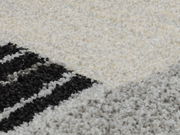 Nahaufnahme eines Teppichs mit geometrischem Muster in Schwarz, Weiß und Grau.