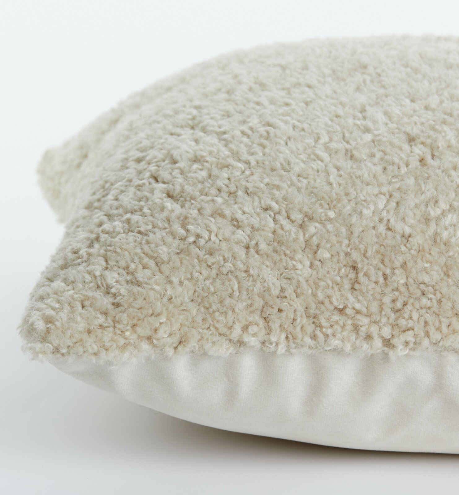 Nahaufnahme eines beigen Kissens mit flauschiger Textur, seitliche Perspektive